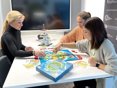 Drei Frauen spielen an einem weißen Tisch das Energiesparspiel